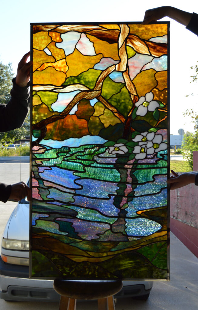 Master Craftsman artists holding one of the completed panels for the FCCCC corridor window.